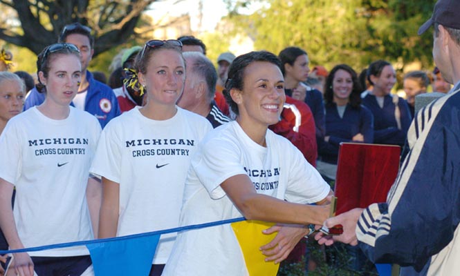 Katie Erdman accepts the team plaque on behalf of the Michigan women, who edged out Illinois for the victory, 77 to 82.